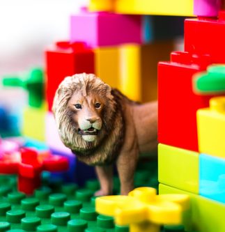 schleich male lion peeks out from behind a duplo block castle