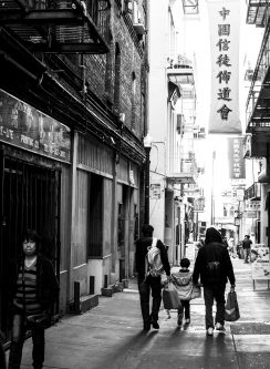 a child, mother, and father walking down a chinatown alley in san francisco, california