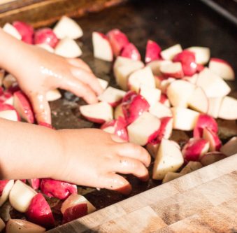 toddler tossing cut potatoes, cooking with toddlers