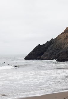 surfers and cliffside at rodeo beach, marin headlands, marin county, california